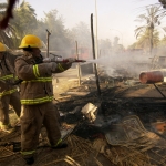 Civilian Contractors Halliburton firemen fight a fire that was reportedly started after someone tried to steal electricity from a nearby power line at an Iraqi market place within the green zone of Baghdad, Iraq (IRQ), during Operation IRAQI FREEDOM