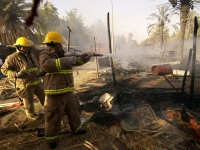 Civilian Contractors Halliburton firemen fight a fire that was reportedly started after someone tried to steal electricity from a nearby power line at an Iraqi market place within the green zone of Baghdad, Iraq (IRQ), during Operation IRAQI FREEDOM