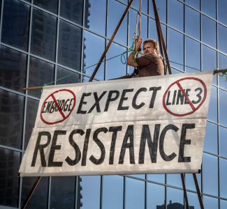 Line 3 protester with an Expect Resistance sign outside the MN Public Utilities Commission